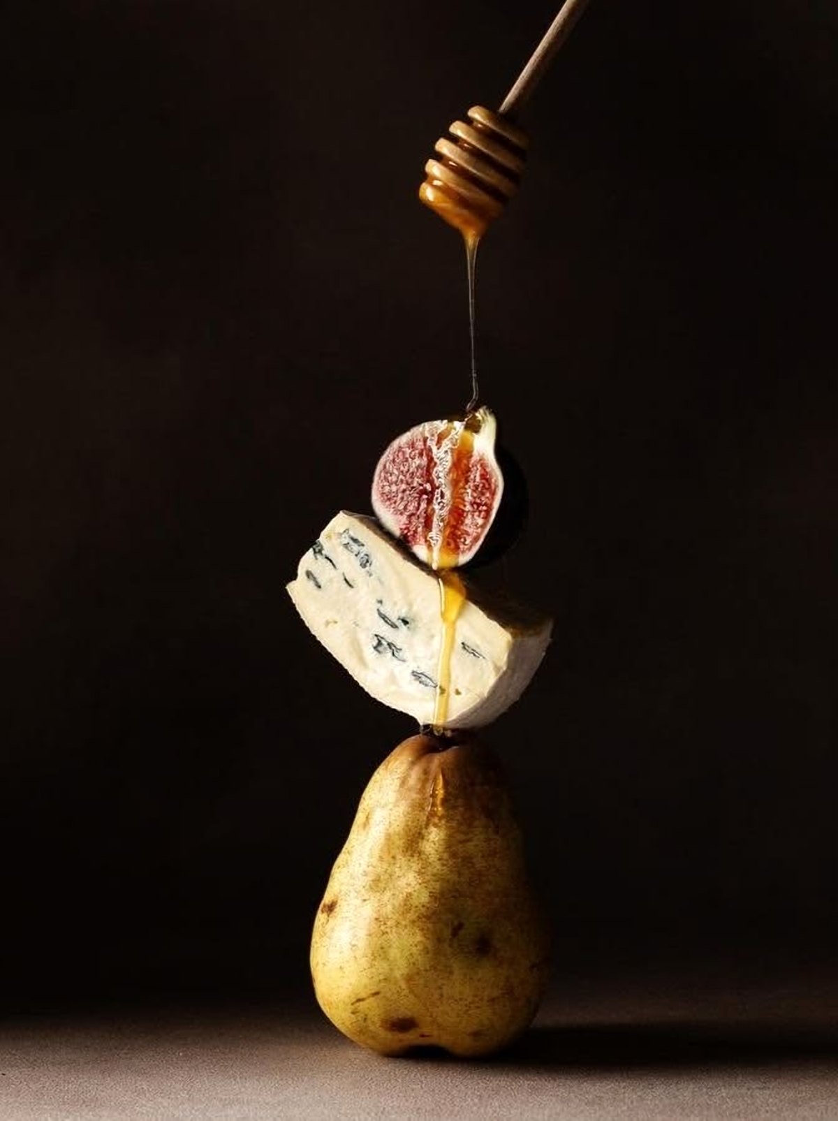 Honey drizzling over fig, blue cheese and a pear