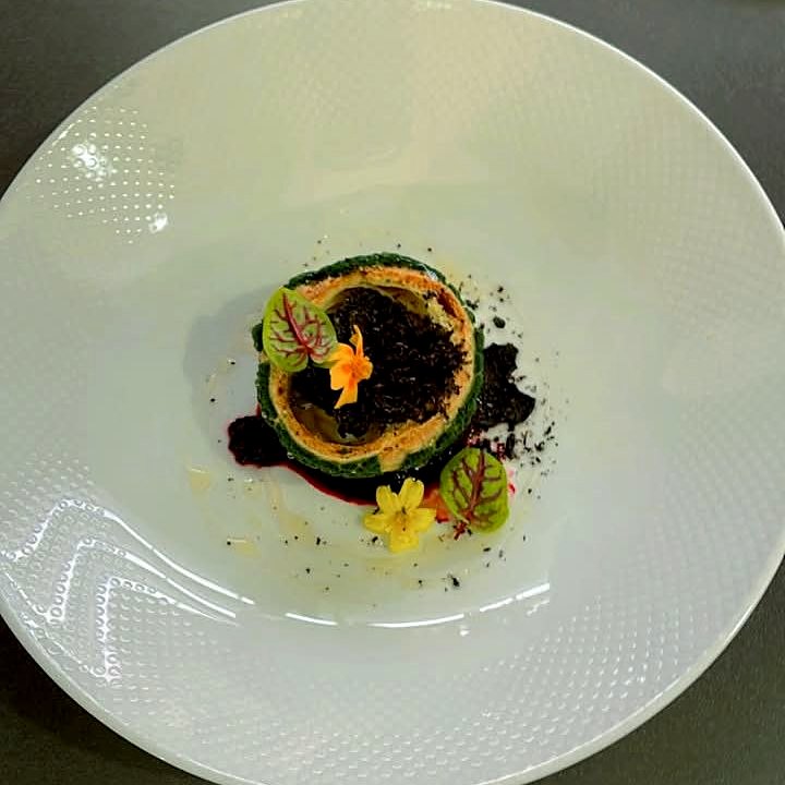 A delicate tart with dark crumb, edible flowers and micro leaves